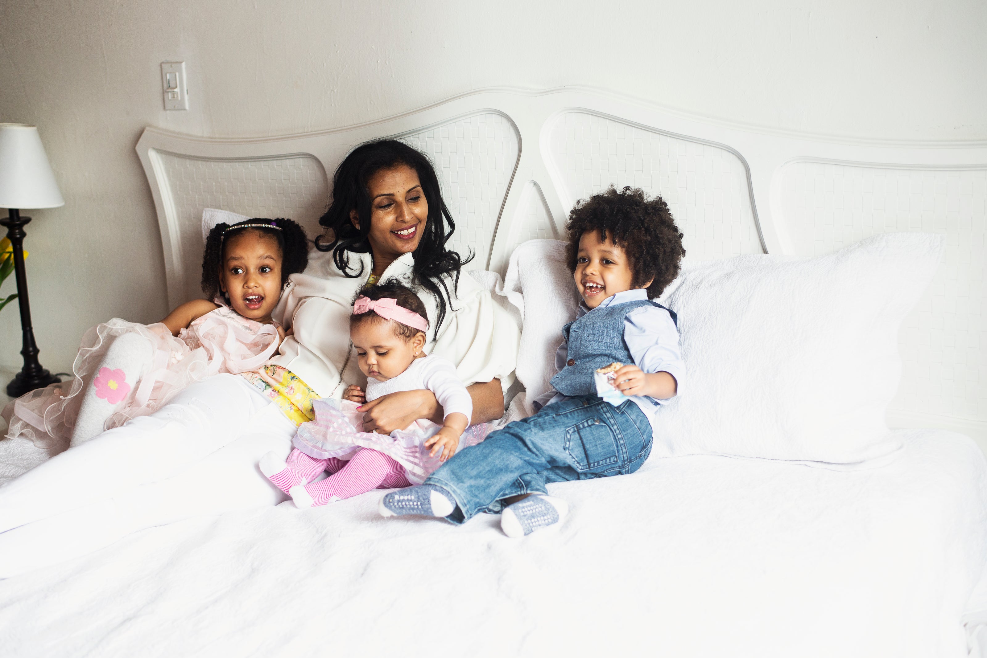 A mother with her three kids in bed smiling 